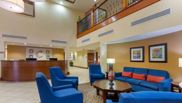 A lobby with a reception desk, blue seating area, and artwork on the walls. - Comfort Suites Charleston West Ashley (Charleston)