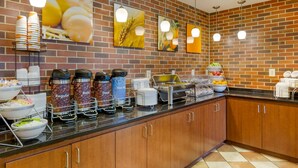 A breakfast bar with coffee dispensers, a fruit bowl, and a bread basket. - Comfort Suites Charleston West Ashley (Charleston)