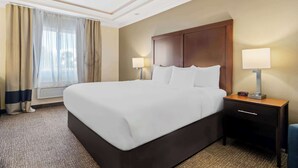 A hotel room with a large bed, two bedside tables with lamps, a window with curtains, and a carpeted floor. - Comfort Inn Hebron-Lowell Area (Hebron)