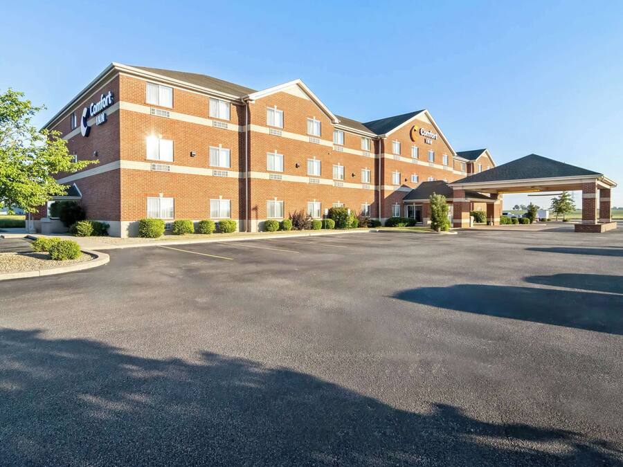 Un hotel Comfort Inn con fachada de ladrillo, múltiples ventanas y un área de estacionamiento techada.