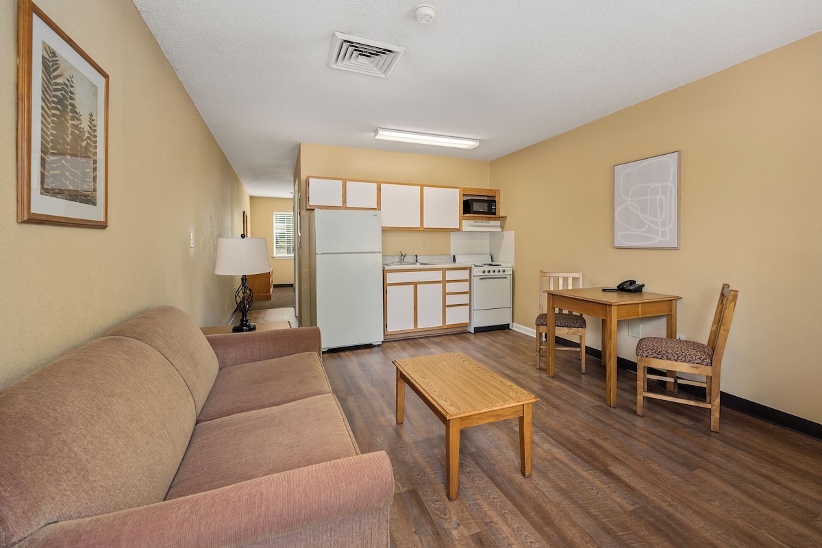 A compact living space with a kitchenette, a sofa, a coffee table, and a dining area.
