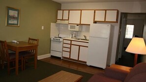 Una cocina compacta con electrodomésticos básicos, una mesa de comedor con sillas y un sofá.