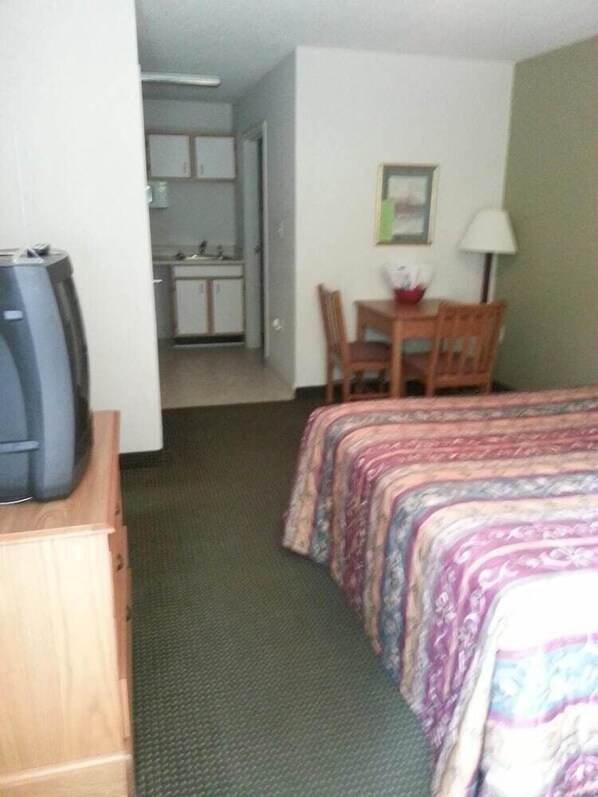 Una habitación de hotel con una cama, un escritorio y una televisión.
