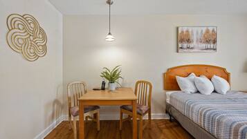 A bedroom with a wooden bed, a bedside table with a plant, and a wall art piece.