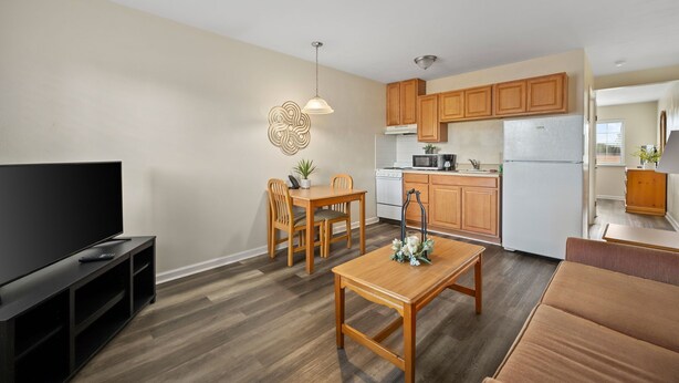 Un espace de vie compact comprenant un coin repas, une kitchenette et un téléviseur posé sur un meuble.