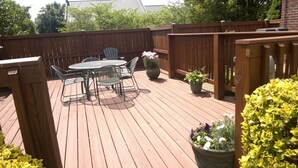 Une terrasse en bois avec une table et des chaises, entourée d’une clôture en bois.