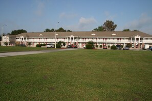 A motel with a central courtyard, multiple balconies, and a parking lot. - Affordable Suites Lexington (Lexington)
