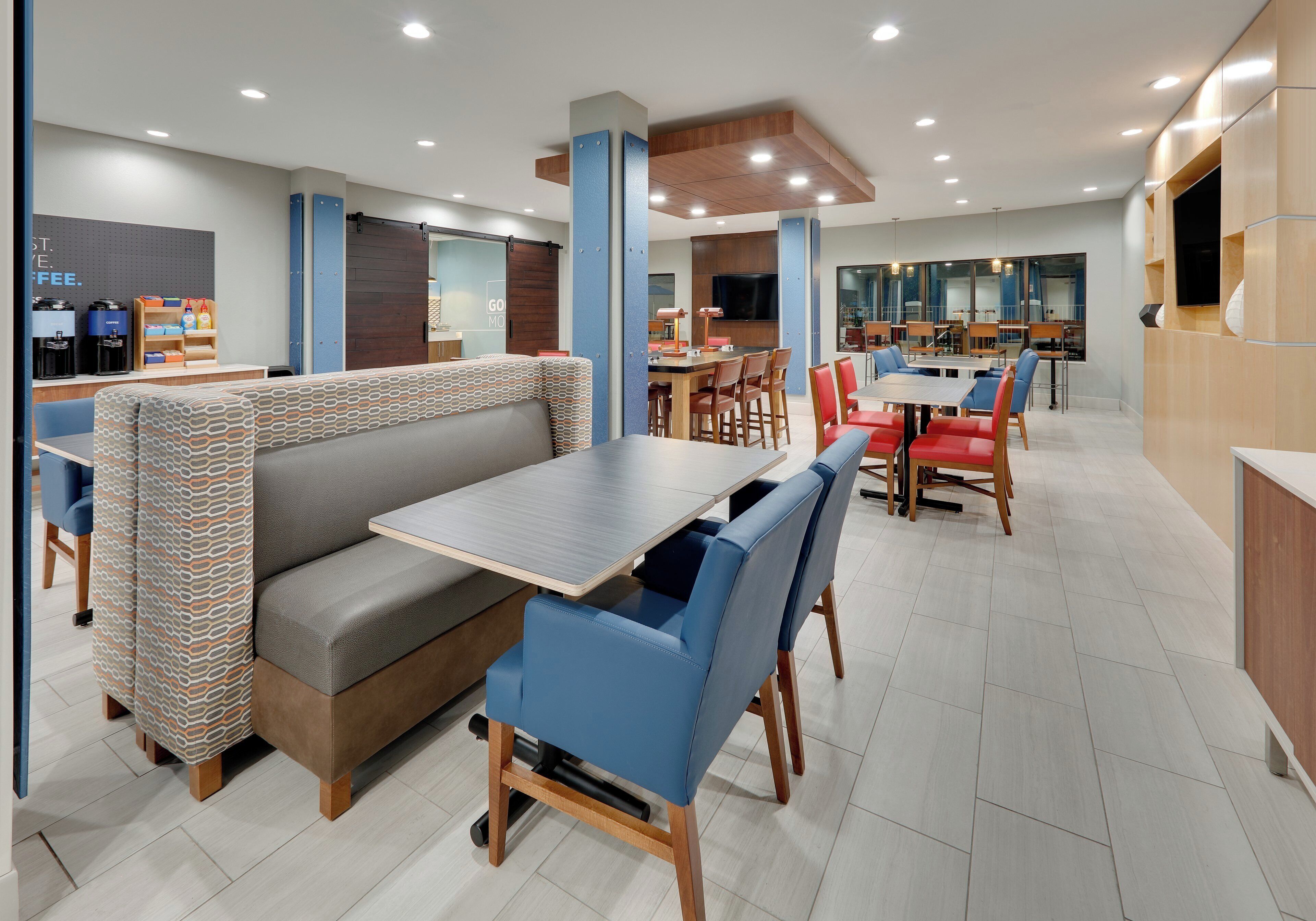 A modern restaurant with a booth seating area, a bar, and a dining area with tables and chairs.