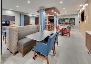 A modern restaurant with a booth seating area, a bar, and a dining area with tables and chairs.