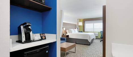 A hotel room with a bed, bedside table, lamp, and a view of the outside.