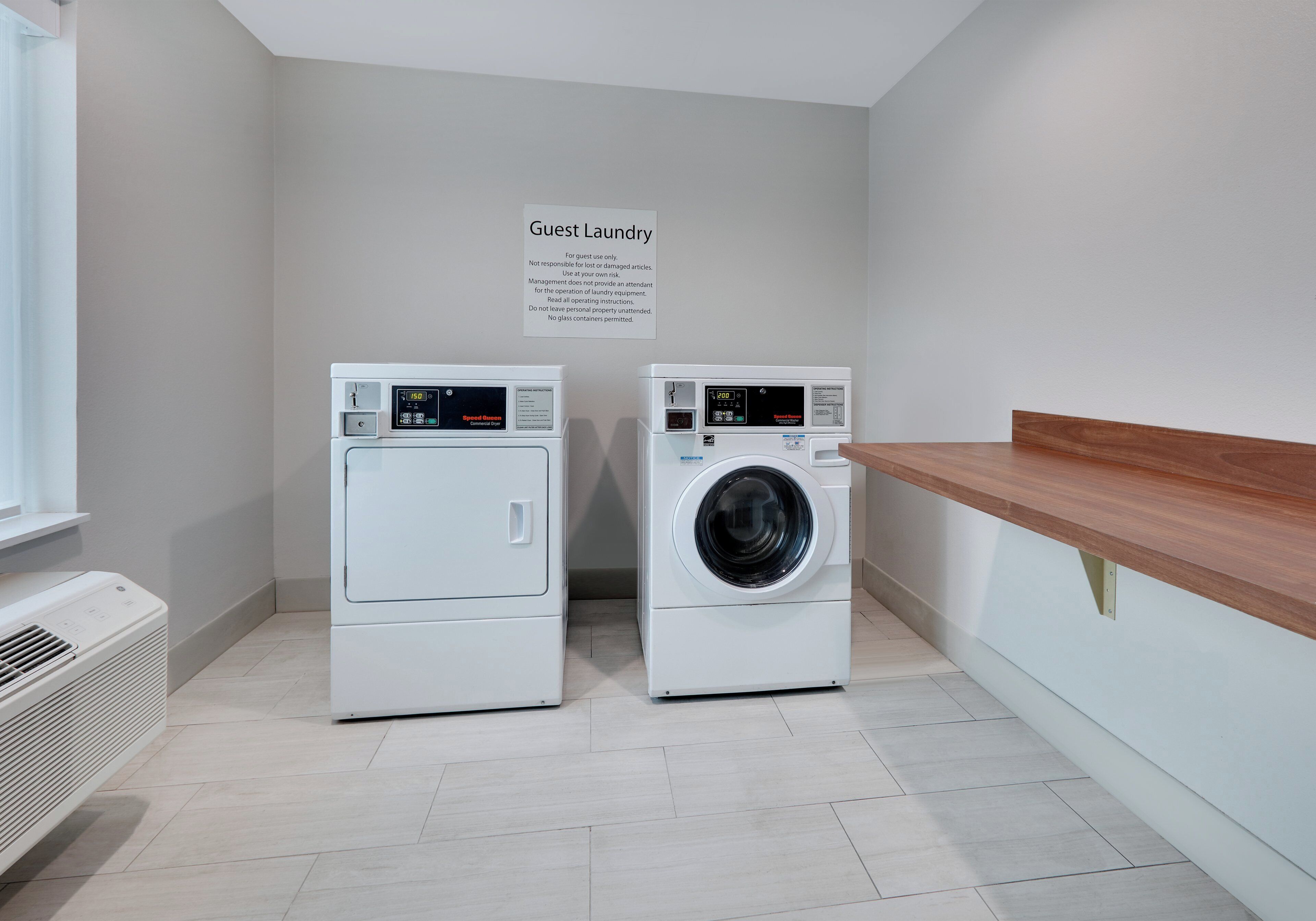 Un espace buanderie équipé de deux sèche-linge et d’un panneau indiquant qu’il est réservé à l’usage des clients.
