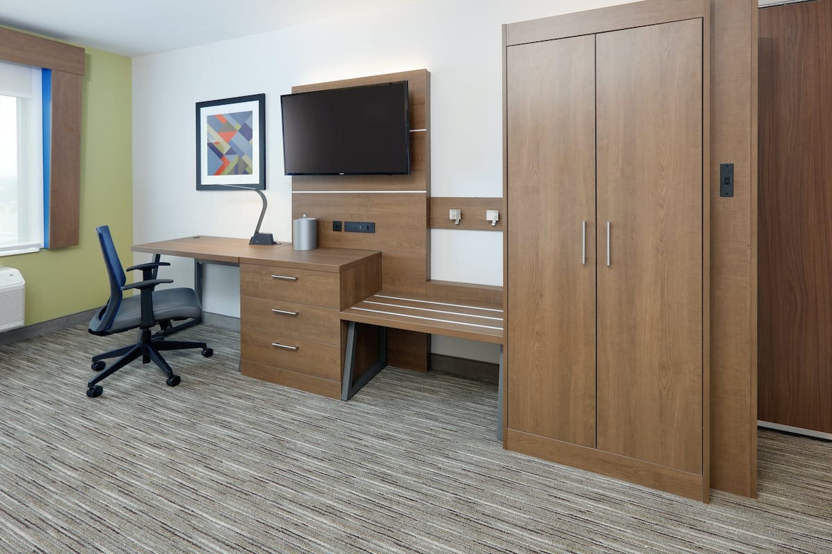 A modern office space with a desk, chair, television, and wardrobe.