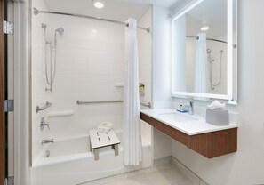 A modern bathroom with a bathtub, shower, and a vanity with a mirror.