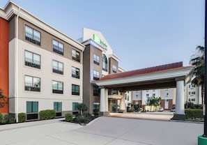 A multi-story hotel with a covered entrance and a parking area.