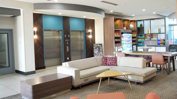 A modern lobby with a sofa, a coffee table, and a seating area with chairs. - Holiday Inn Hotel & Suites PHOENIX AIRPORT by IHG (Phoenix)