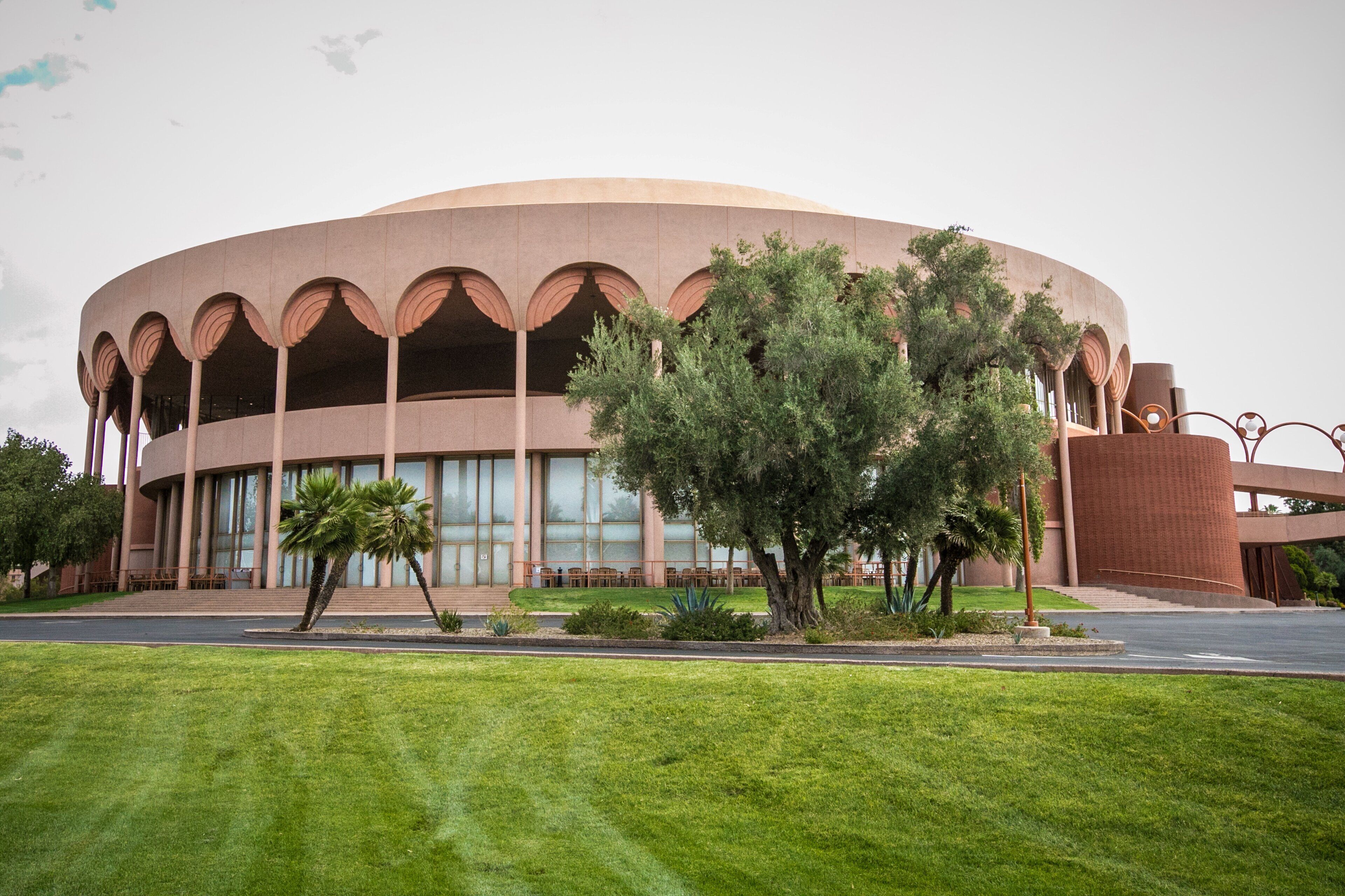 A large, circular building with a central courtyard, surrounded by a well-maintained lawn and trees.