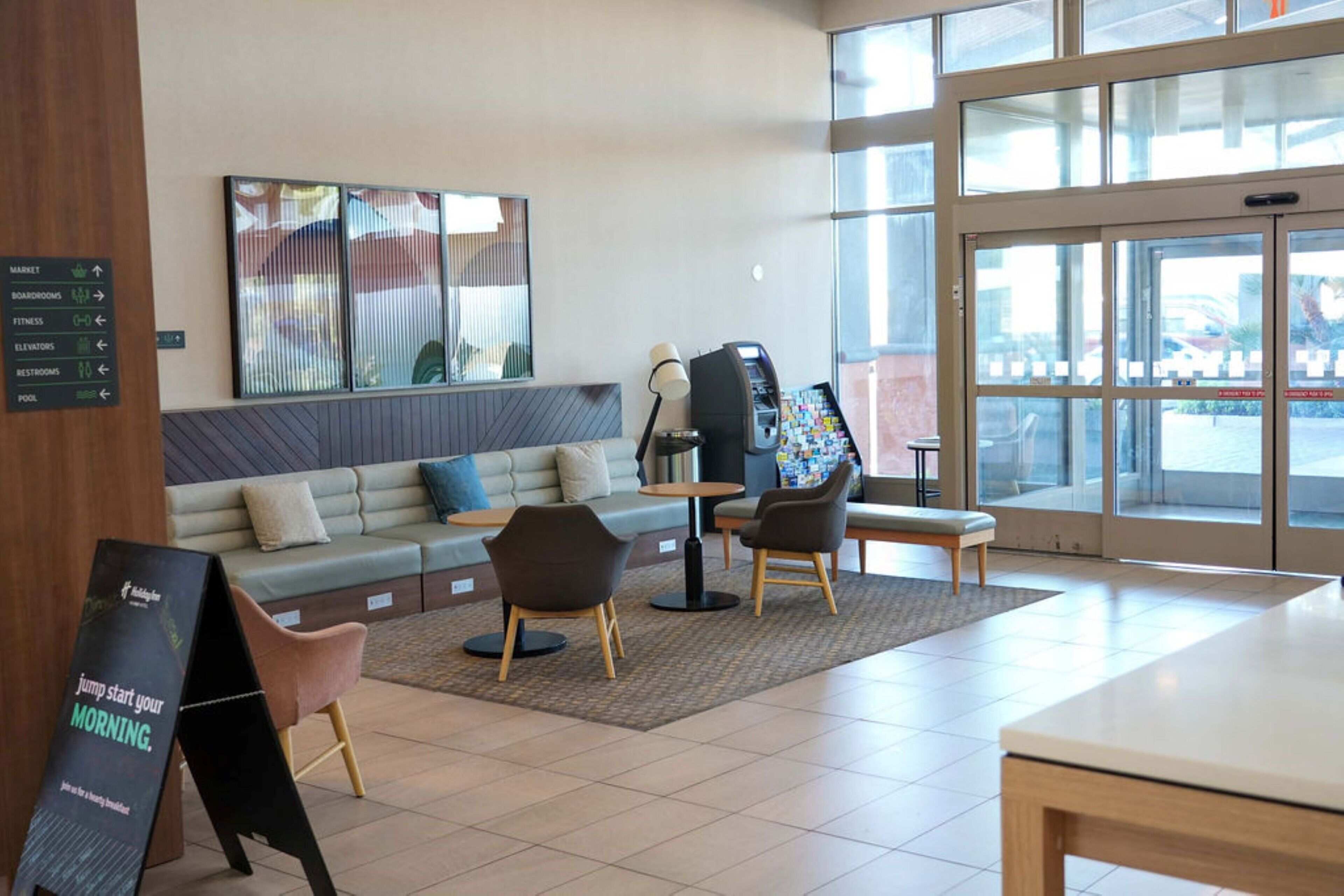 A modern lobby with a seating area, a reception desk, and a large window.