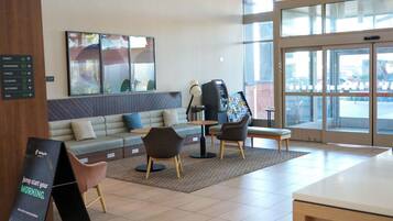 A modern lobby with a seating area, a reception desk, and a large window.
