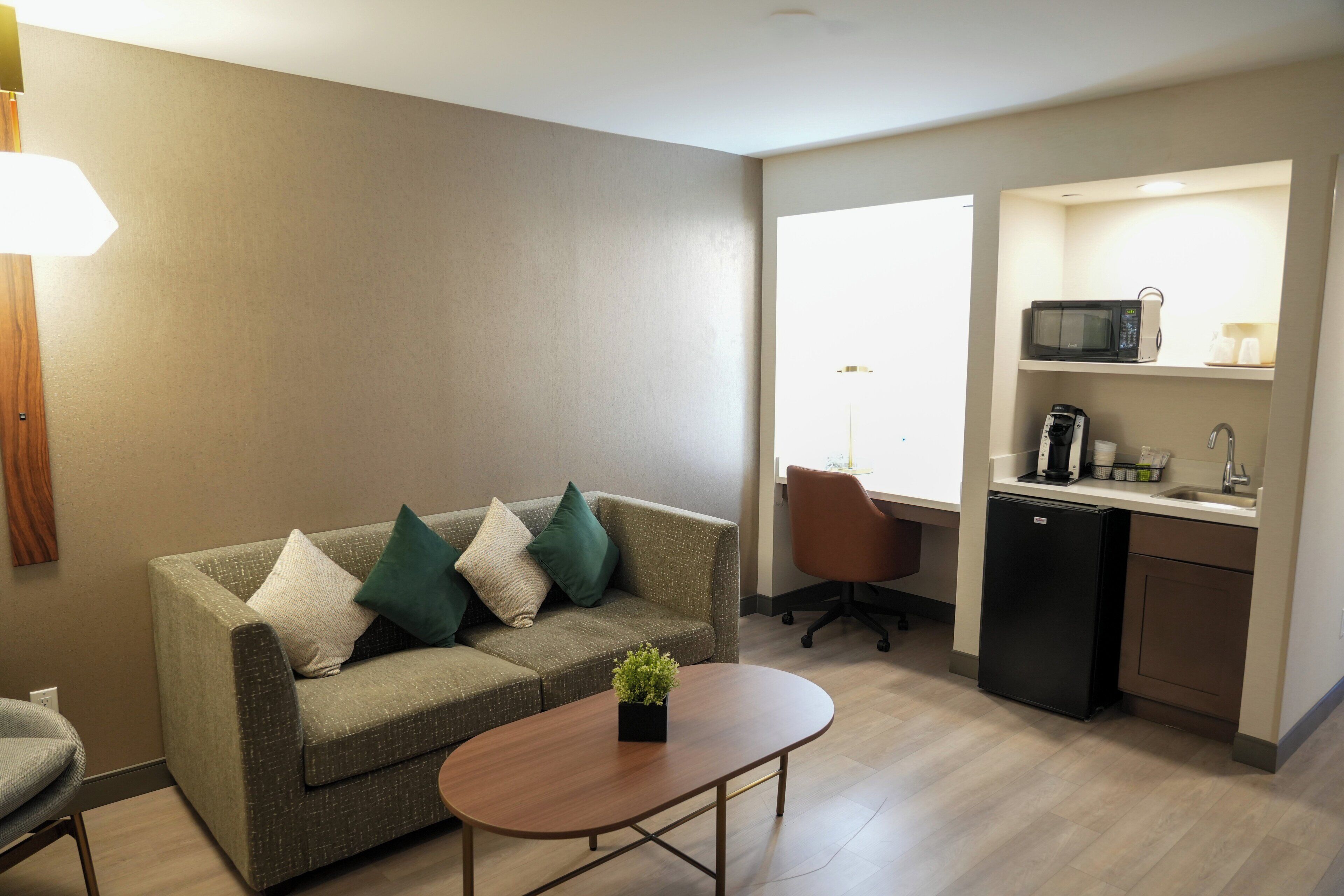 A compact living space with a sofa, a small table, a microwave, and a compact kitchenette.