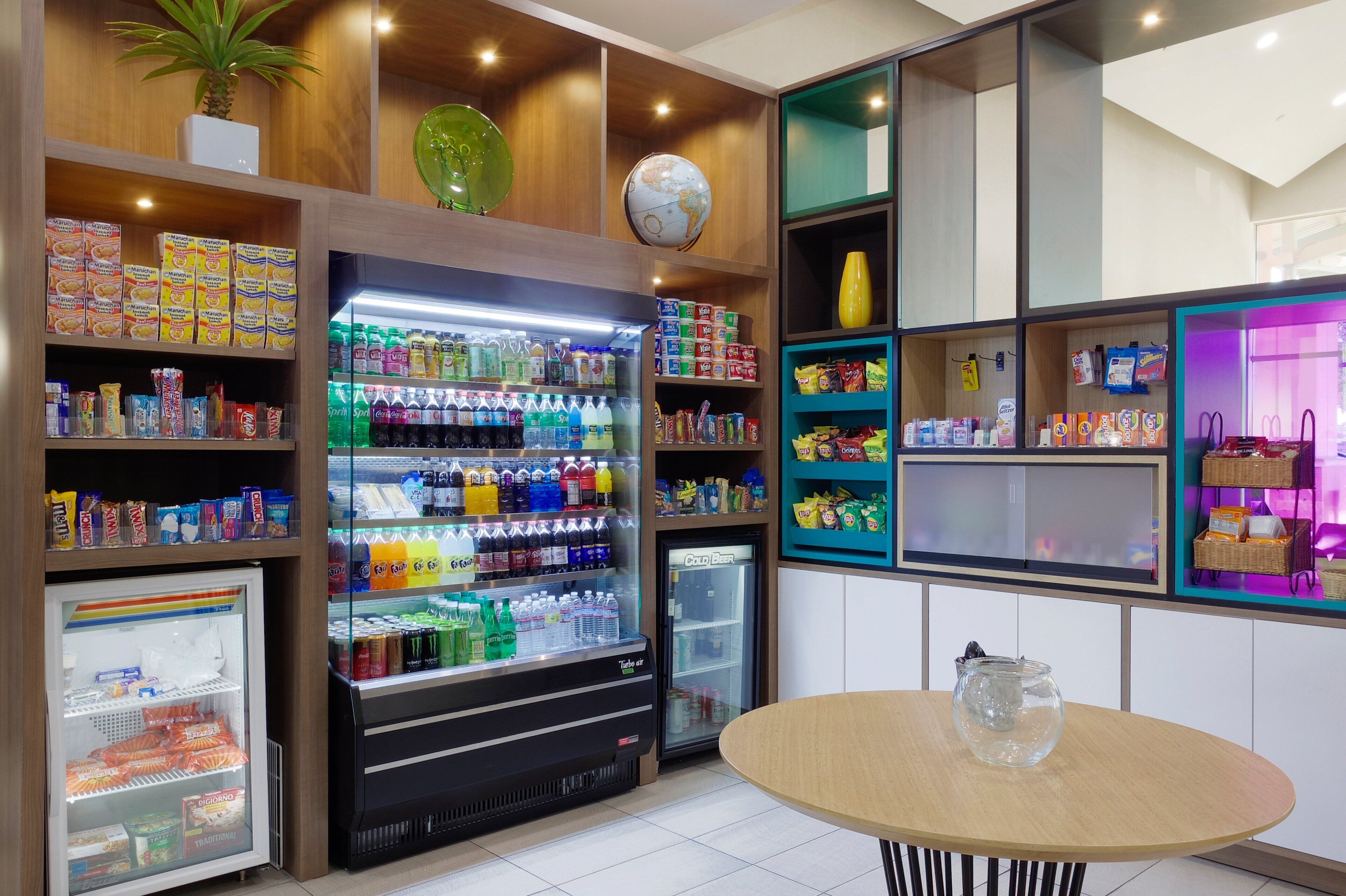 A well-lit snack and beverage vending area with various products, a globe on the wall, and a table with a fishbowl.