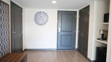 Un couloir avec un banc en bois, une porte grise et un élément décoratif fixé au mur.