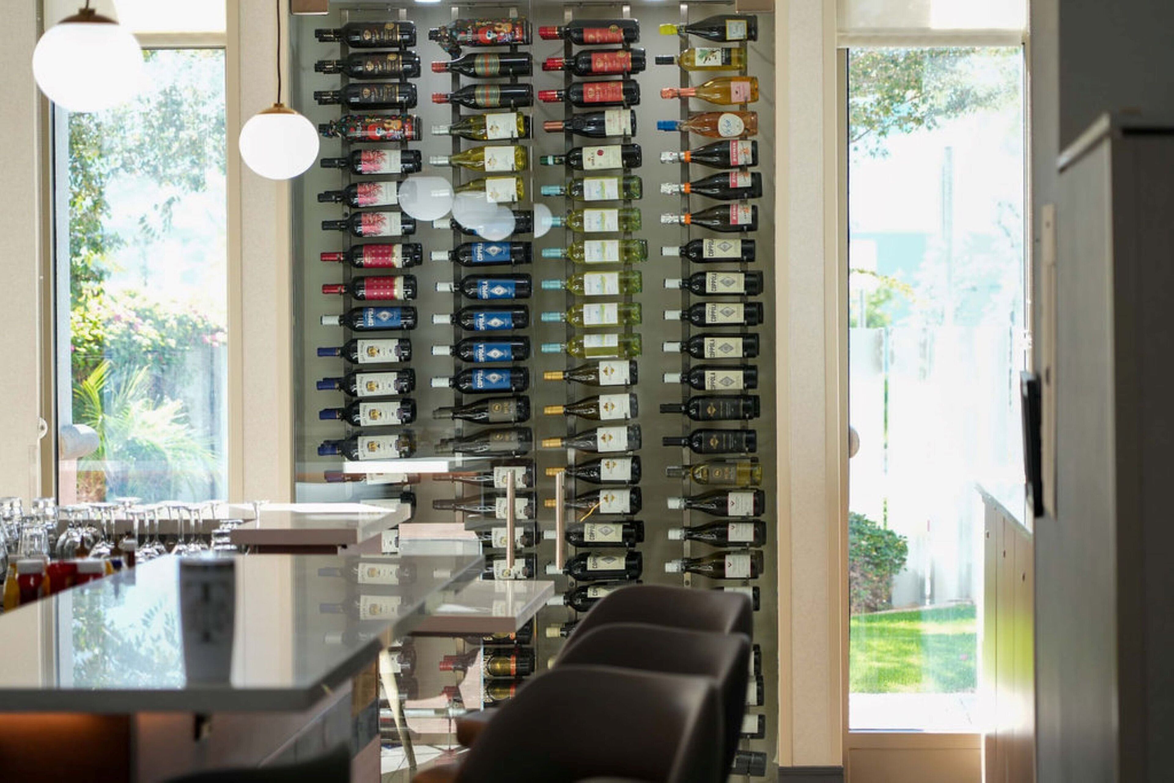 Un espace bar avec un mur entièrement recouvert de bouteilles de vin et de verres.