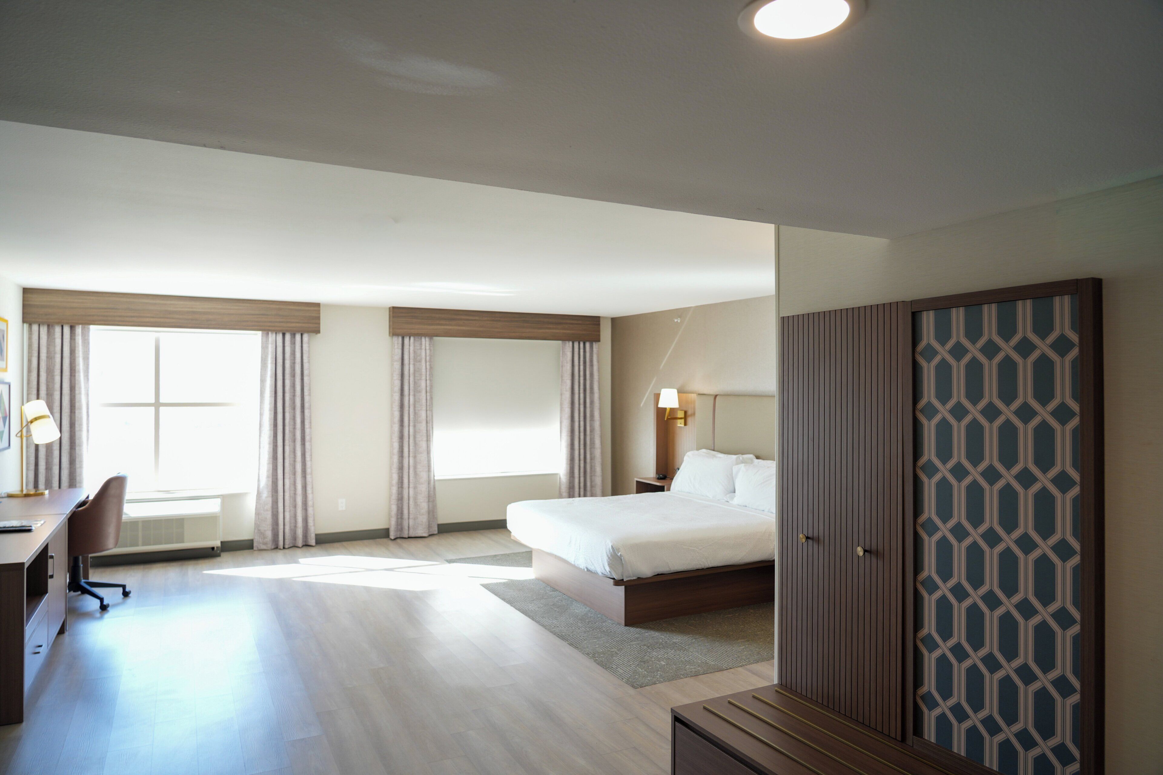 Habitación de hotel con cama, escritorio, silla y armario.