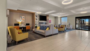 A modern hotel lobby with a sofa, chairs, a TV, and a dining area. - Holiday Inn Express & Suites Oklahoma City NW-Quail Springs by IHG (Oklahoma City)