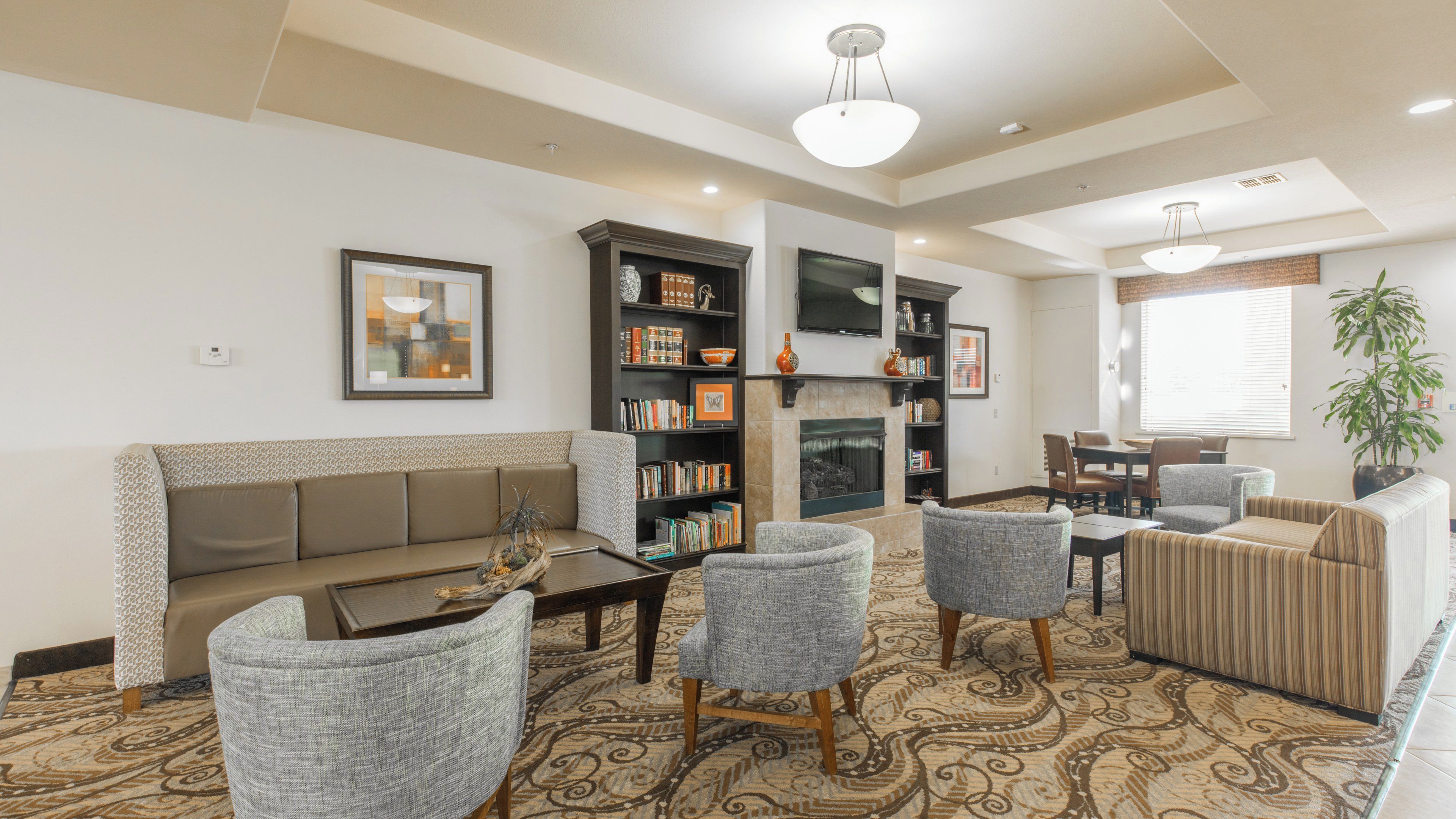 A living room with a sofa, armchairs, a coffee table, a fireplace, and a bookshelf.
