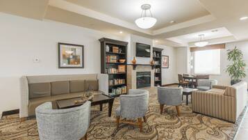A living room with a sofa, armchairs, a coffee table, a fireplace, and a bookshelf.