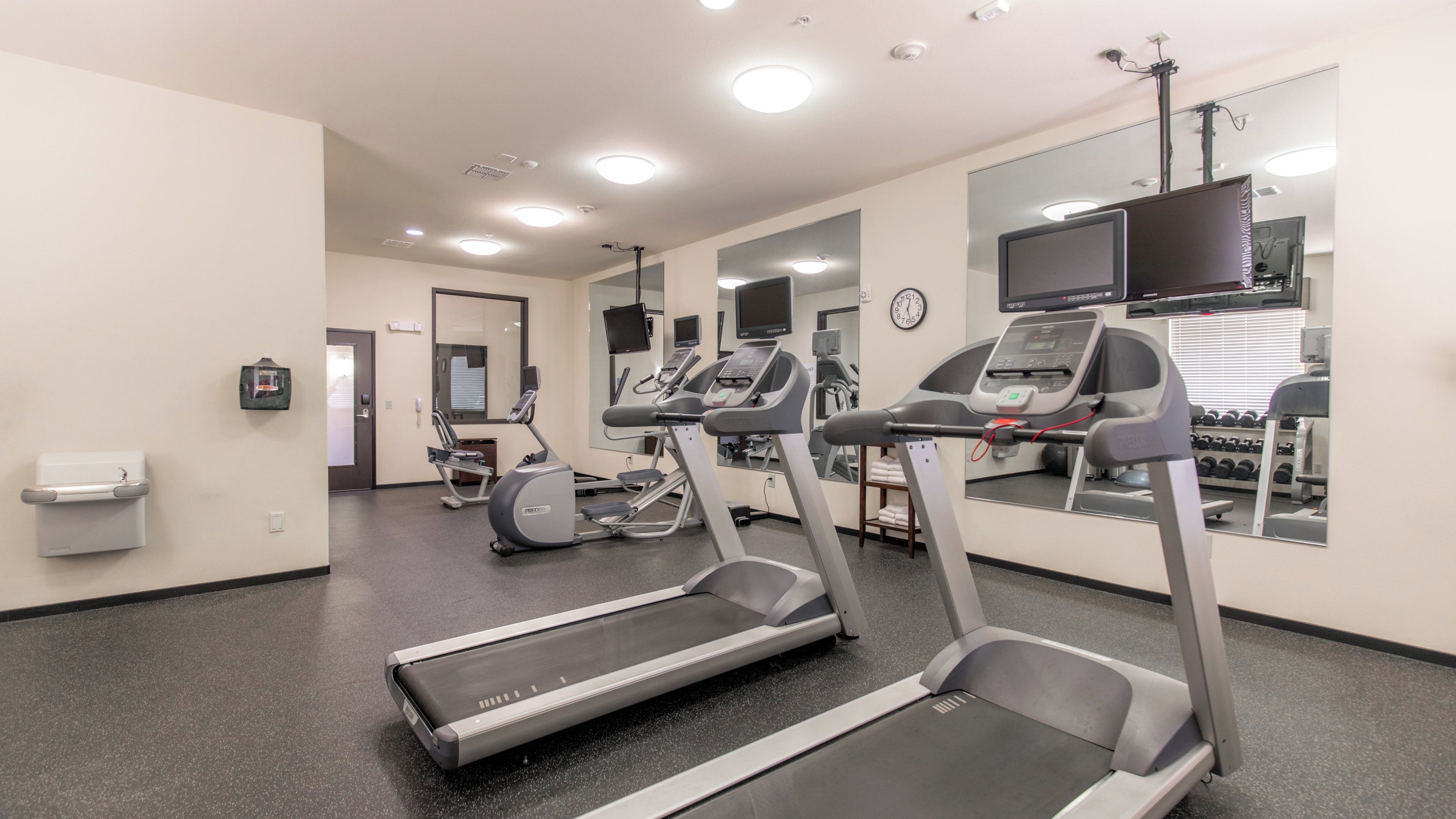 A fitness center with treadmills, exercise bikes, and a mirrored wall.