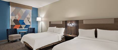 A hotel room with two beds, a small table, a chair, and a decorative wall panel.