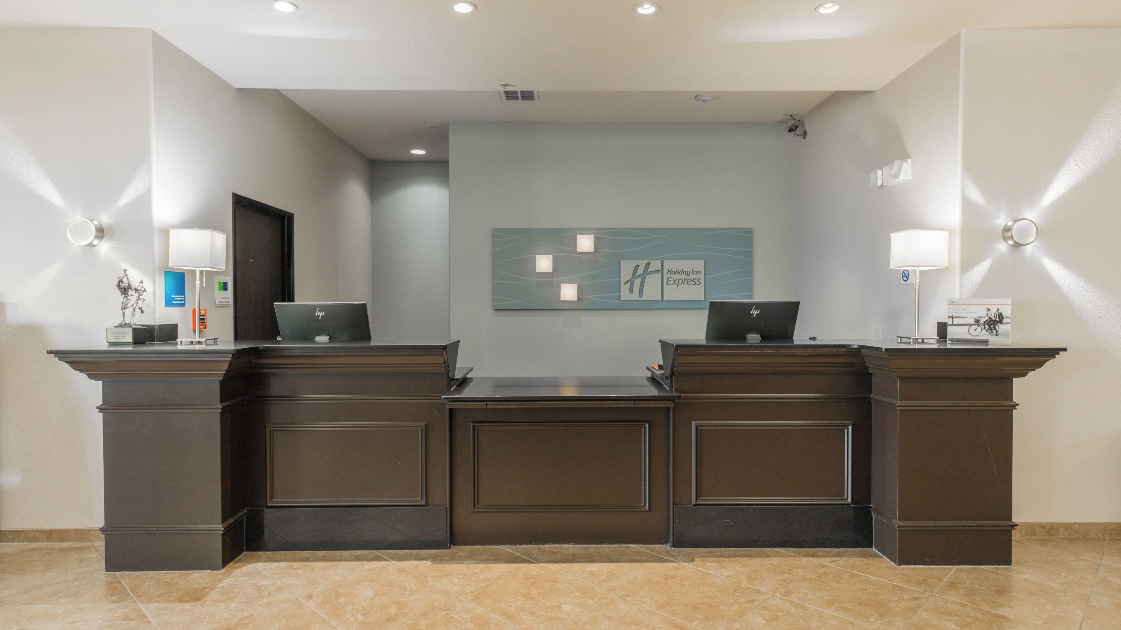 A reception desk with two HP laptops, a Holiday Inn Express sign, and a wall-mounted light fixture.