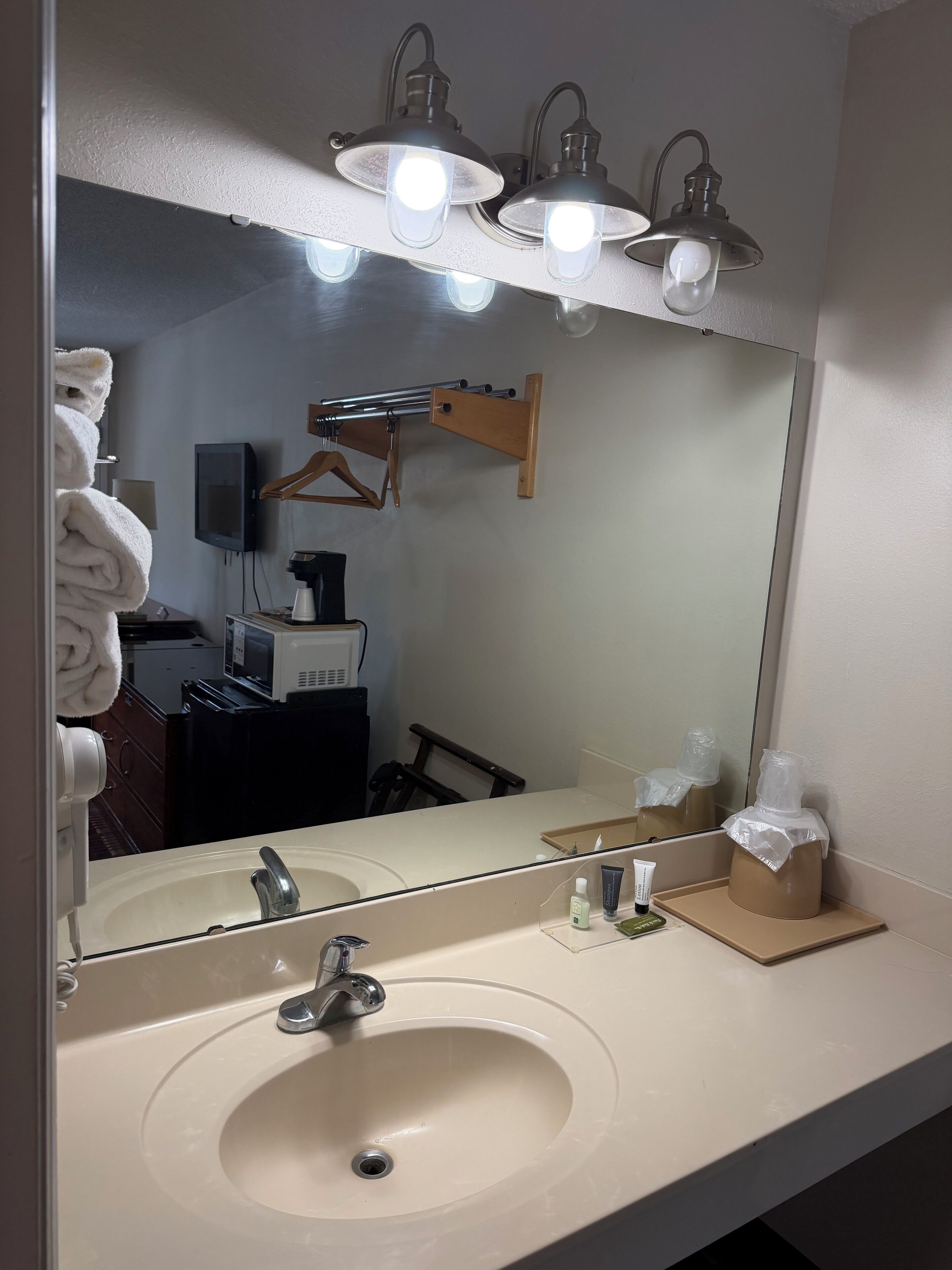 A bathroom with a sink, mirror, towel rack, and a towel.