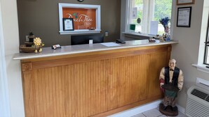 Un mostrador de recepción con un reloj, diplomas enmarcados y una ventana con vistas.