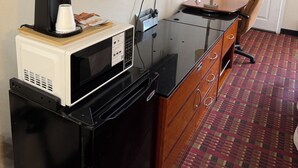 Habitación de hotel compacta con kitchenette, televisión, escritorio y silla.