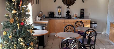 Uma sala de jantar com árvore de Natal, armários de madeira e uma máquina de café.