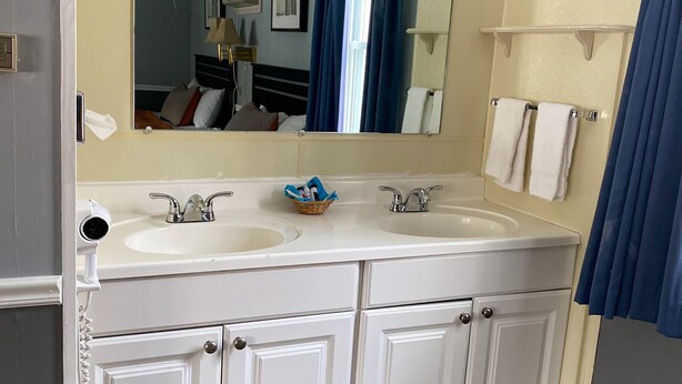 A bathroom with two sinks, a mirror, a towel rack, and a shower curtain. - Travelodge by Wyndham Lincoln Near White Mountain (Lincoln)