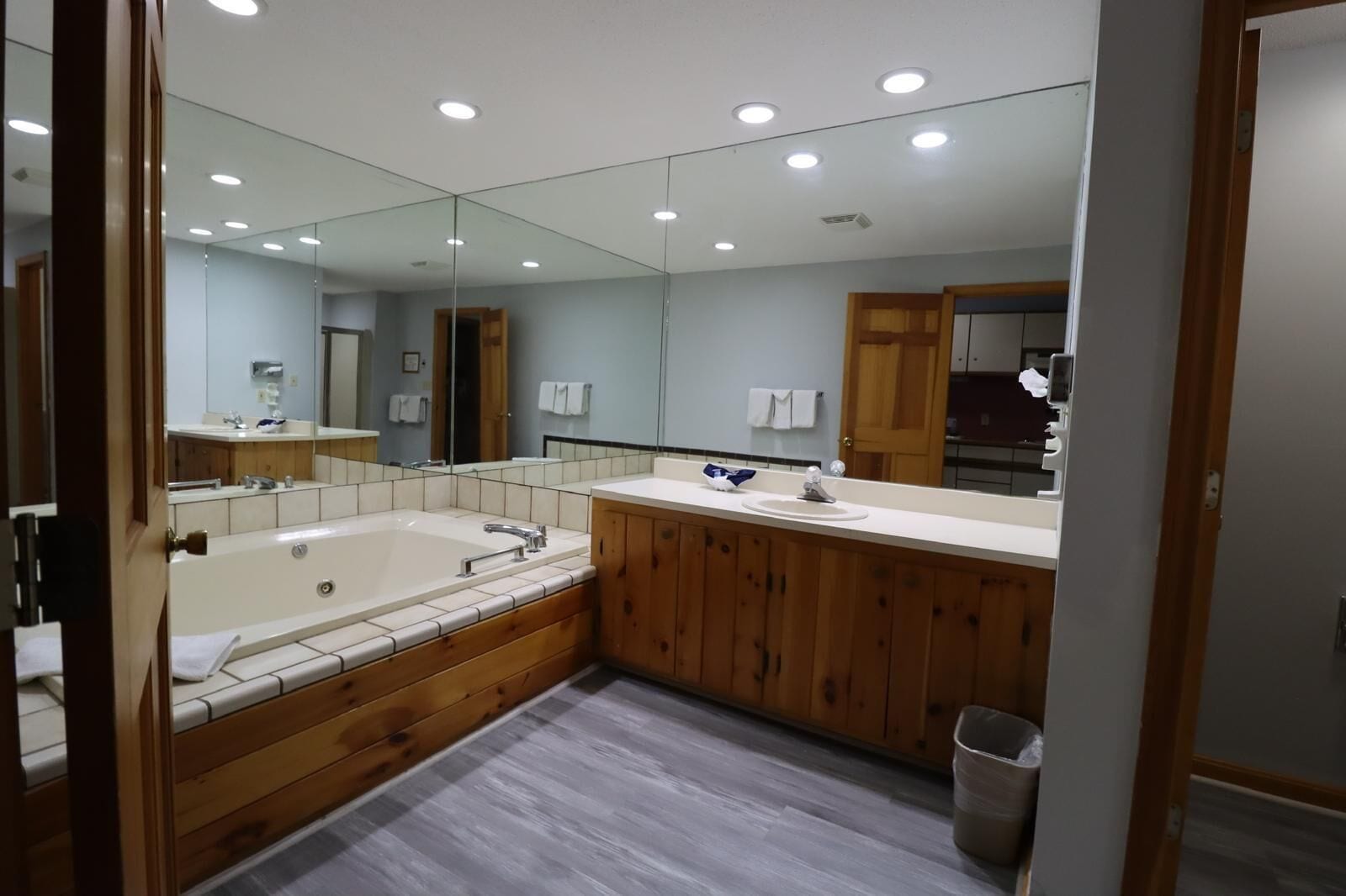 Un baño moderno con una bañera grande, tocador de madera y un espejo.