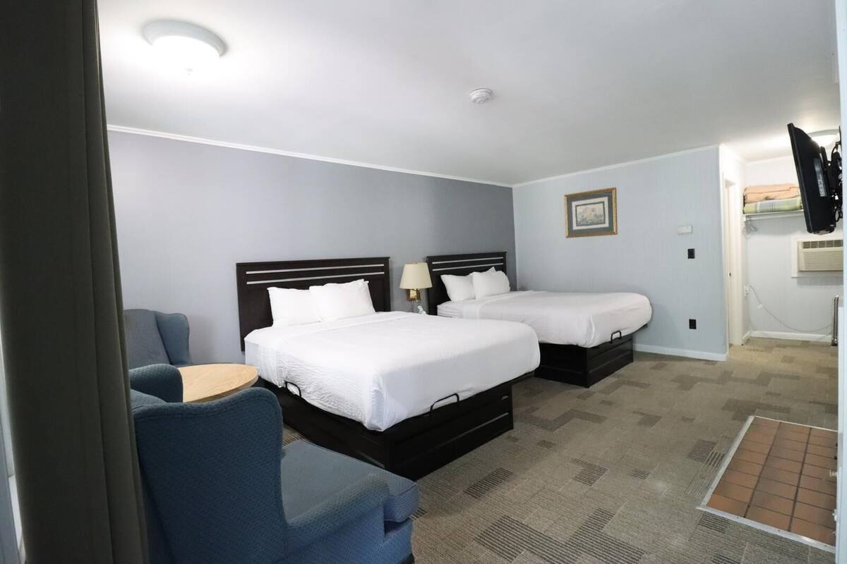 Ein Hotelzimmer mit zwei Betten, einem Schreibtisch und einem Stuhl.