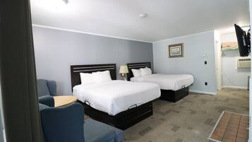 A hotel room with two beds, a desk, and a chair.