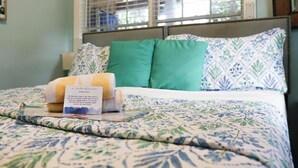 Ein ordentlich bezogenes Bett mit blumigem Muster, zwei Kissen und eine Notiz darauf.
