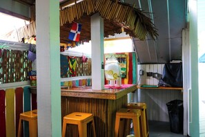 A colorful interior with a bar area, stools, and a flag. - Caribbean House (Key West)