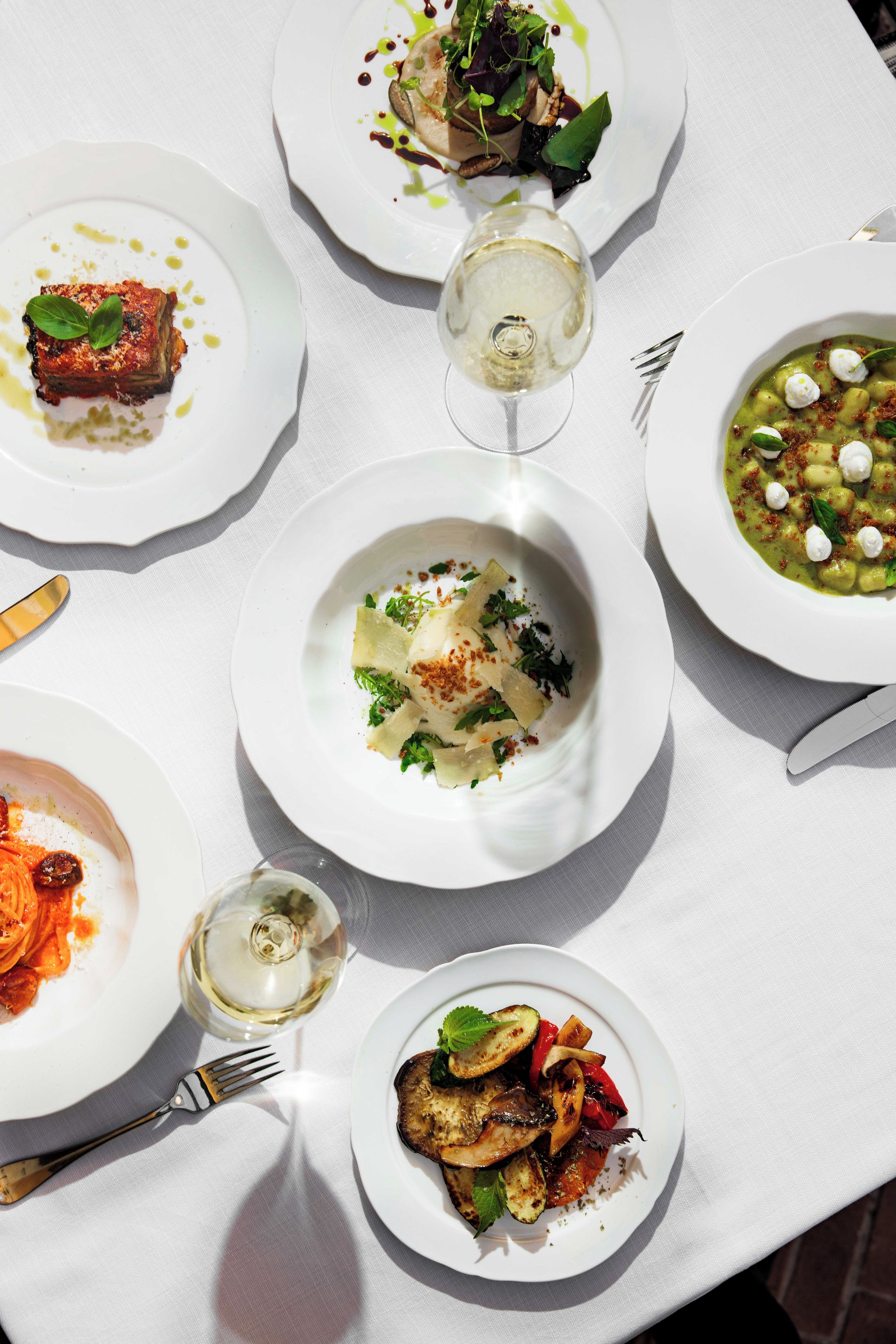 A table set with various dishes, a wine glass, and cutlery.