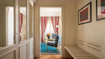 A hallway with a bed, a chair, and a table with a vase of flowers.