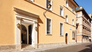 A yellow building with a grand entrance, multiple windows, and a cobblestone street. - Palazzo Ripetta (Rome)