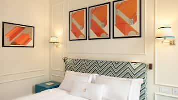 Habitación de hotel con una cama, una mesita de noche, una lámpara y tres cuadros enmarcados en la pared.