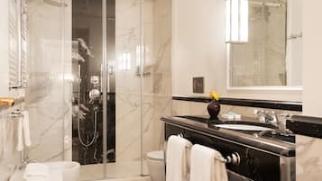 Un baño moderno con cabina de ducha de vidrio, tocador con lavabo y espejo.