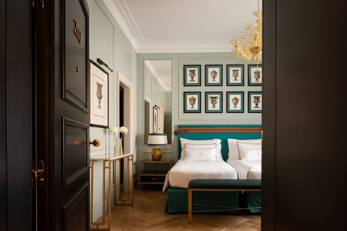 A bedroom with a large bed, a bedside table, a mirror, and framed artwork on the wall.