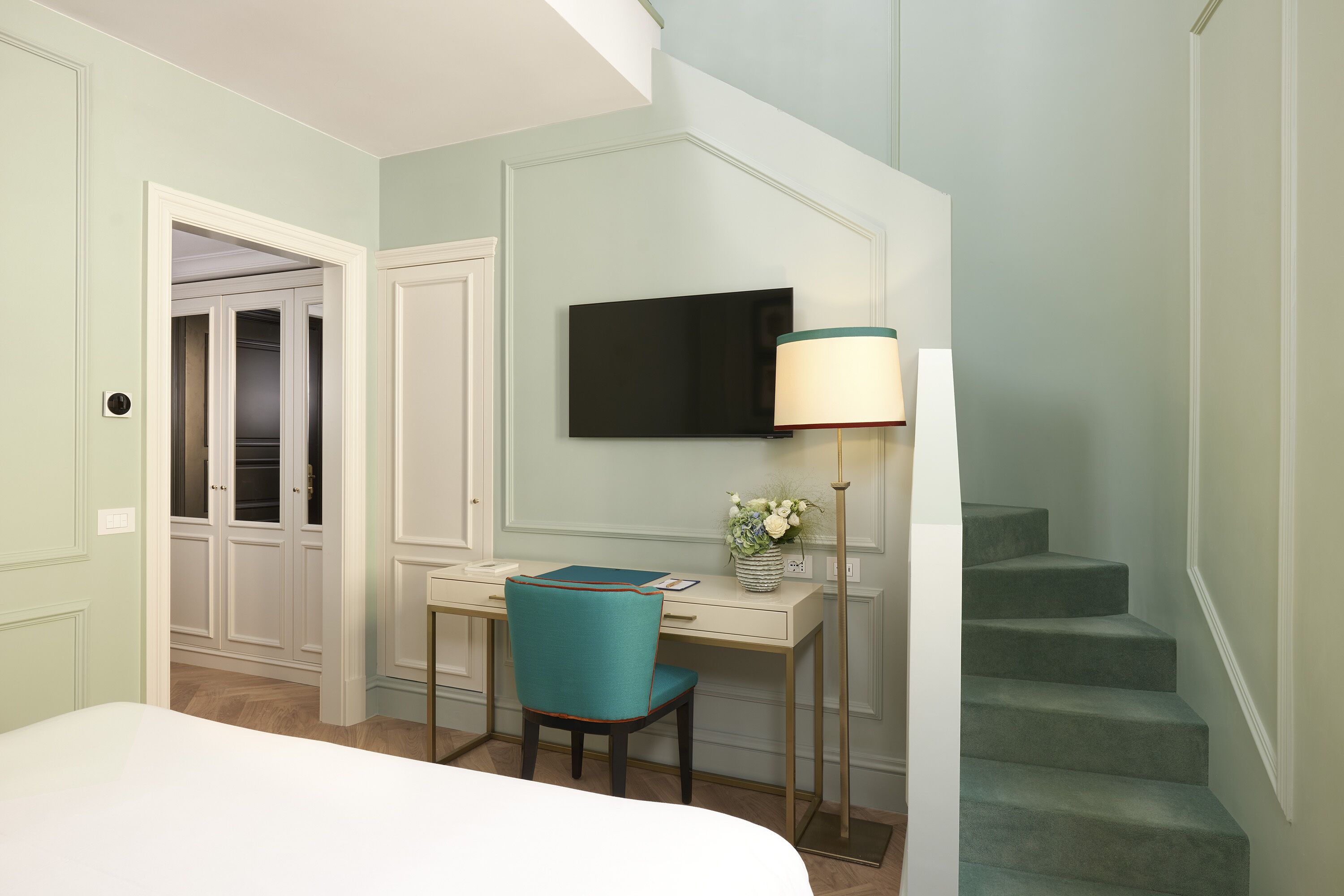 Une chambre d’hôtel comprenant un lit, un bureau avec une chaise, une télévision et un escalier.